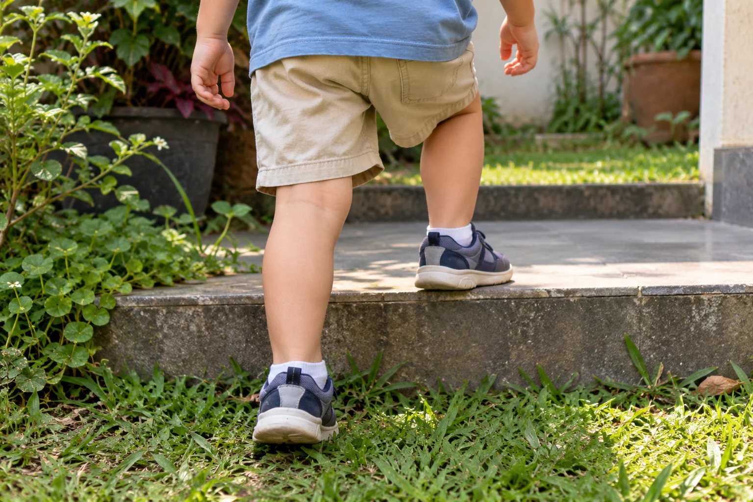 Detail pakaian dan kaki anak saat melangkah di taman